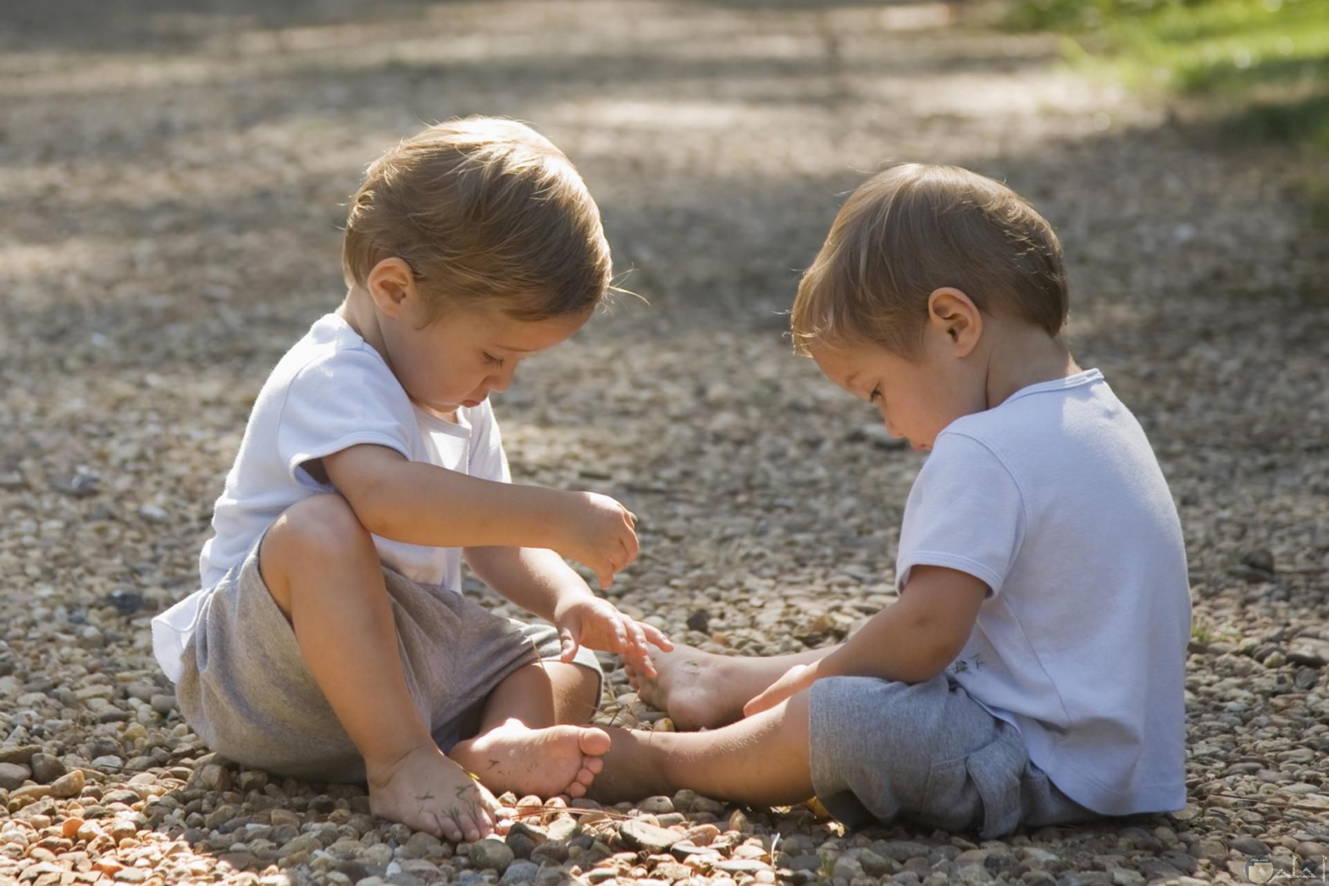 صورة جميلة لطفلين توأن يلعبون سوياً علي الأرض