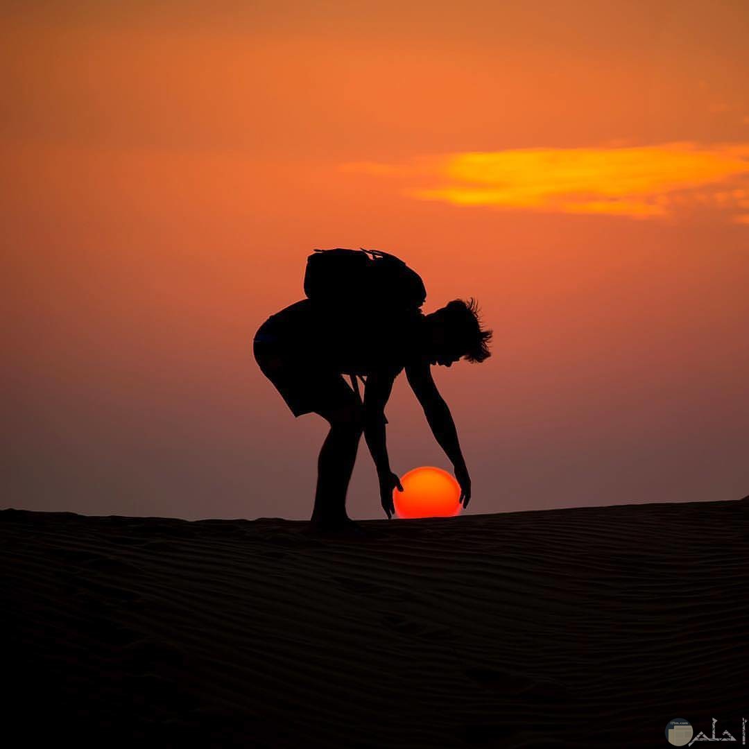 صورة غريبة لغروب الشمس مع رجل يمسكها