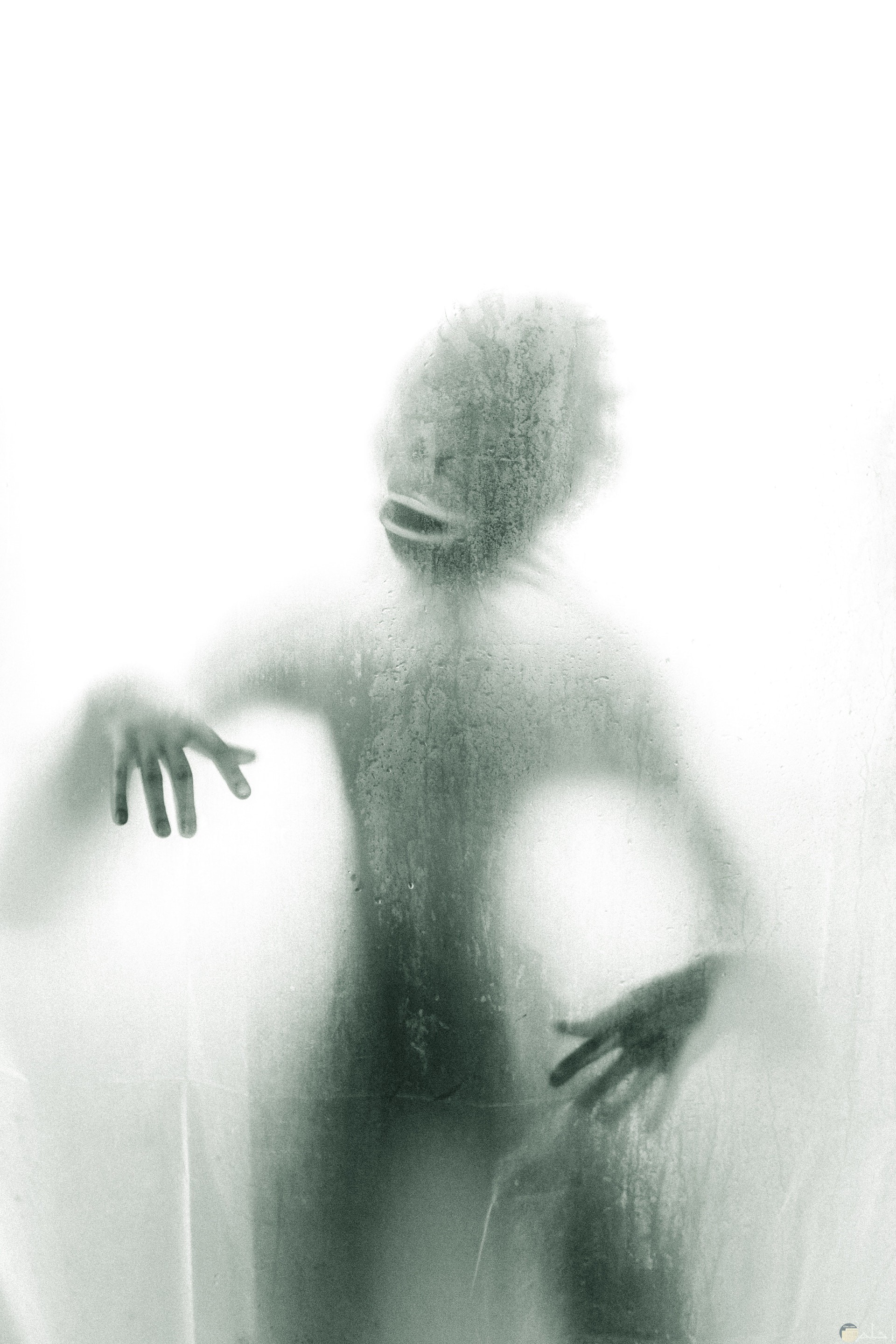 صورة مرعبة ومخيفة لكائن غريب خلف باب شبه شفاف 