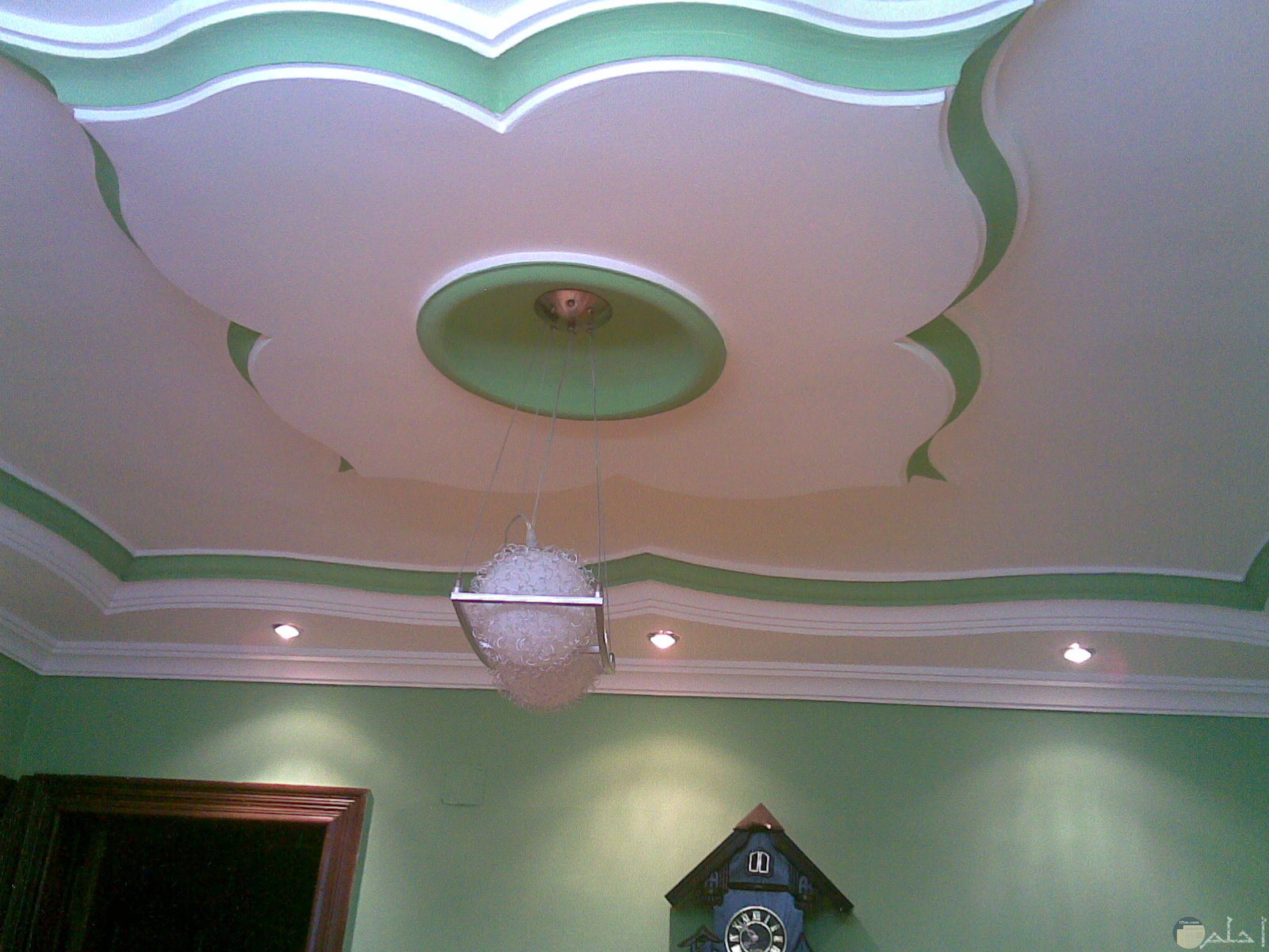 سقف من الاسمنت علي شكل ورده ابيض في اخضر وبالنصف نجفه بيضاء