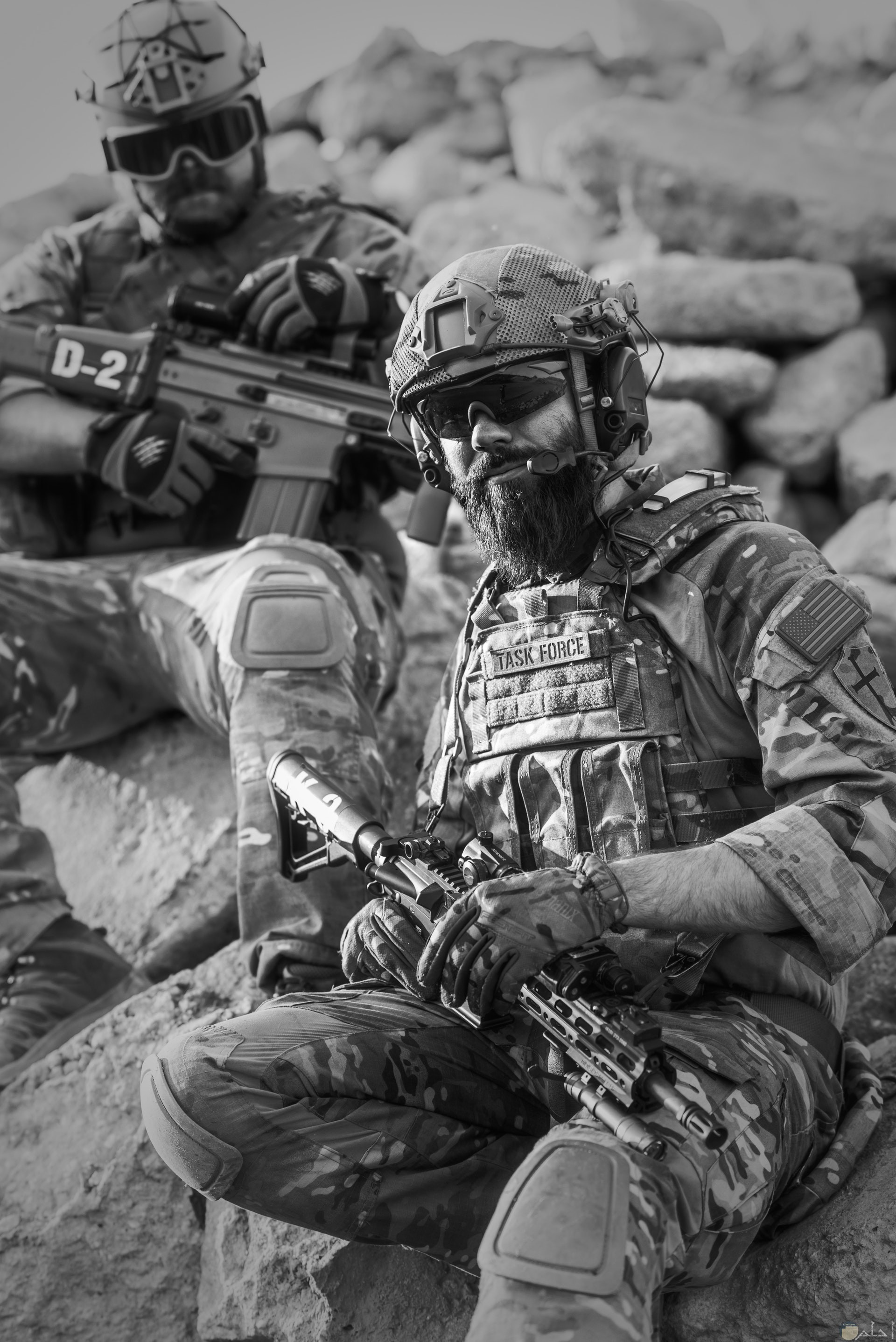 صورة أكشن مميزة بالأبيض والأسود لمجندين يحملان سلاح ويجلسان علي الصخر
