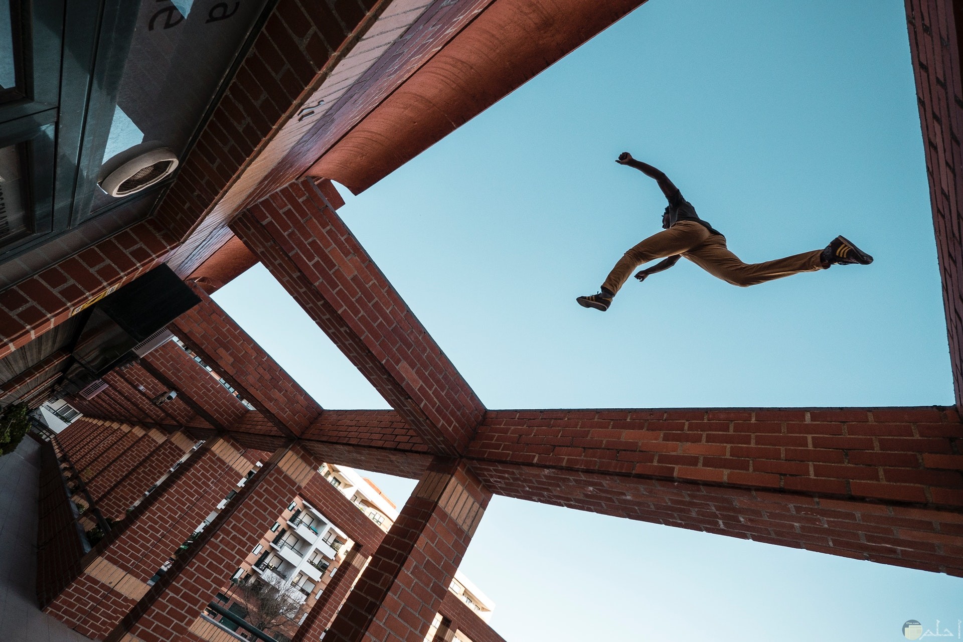 صورة أكشن مميزة لشخص يقفز عاليا من نقطة لنقطة أخري فوق مبني