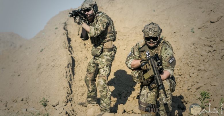 صورة أكشن مميزة لمجندين يحملان سلاح وواقفان يراقبان شيء ما في الصحراء