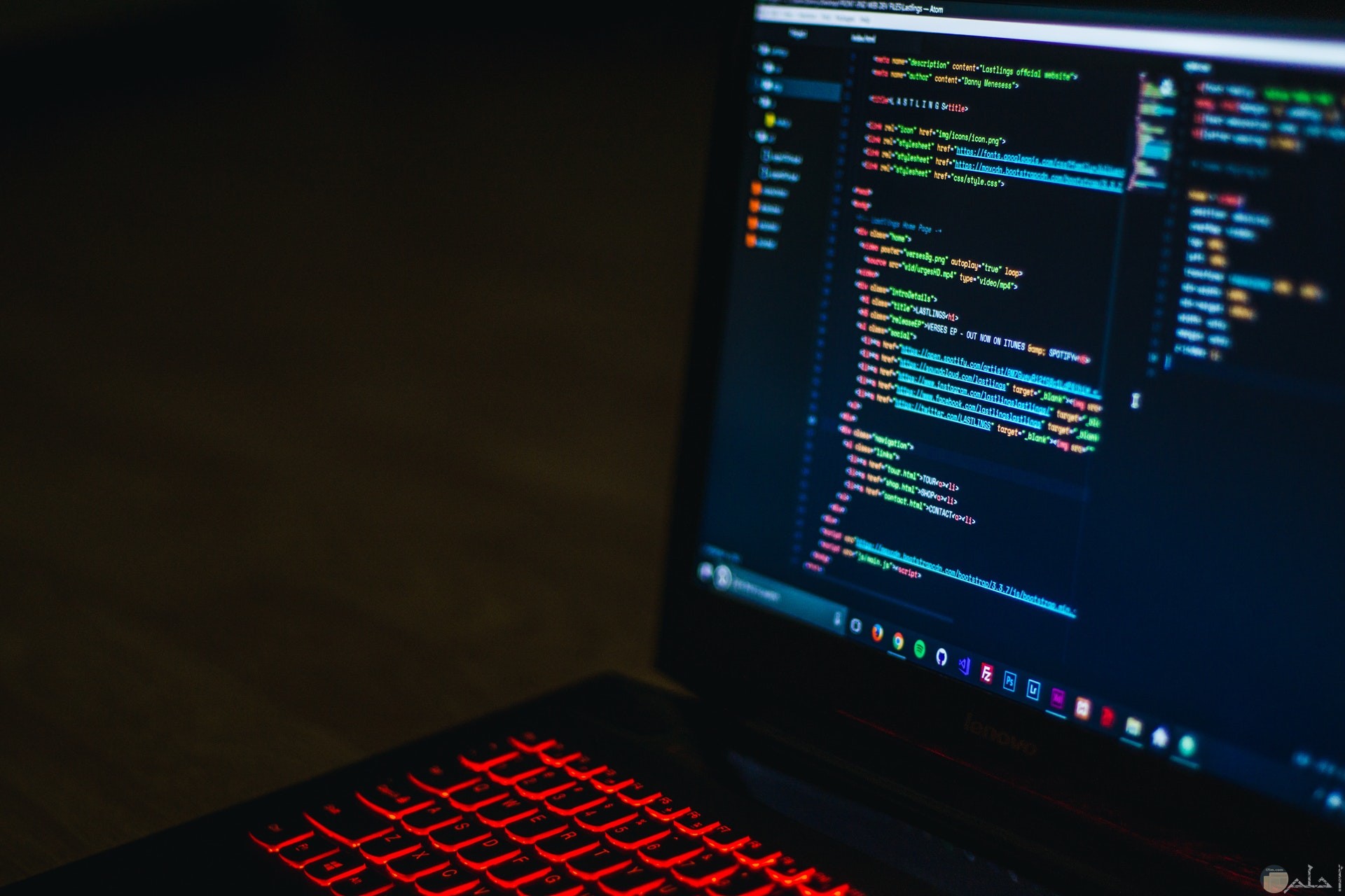 صورة تكنولوجيا مميزة لحاسوب علي شاشته أكواد برمجة ولوحة مفاتيح مضيئة باللون الأحمر