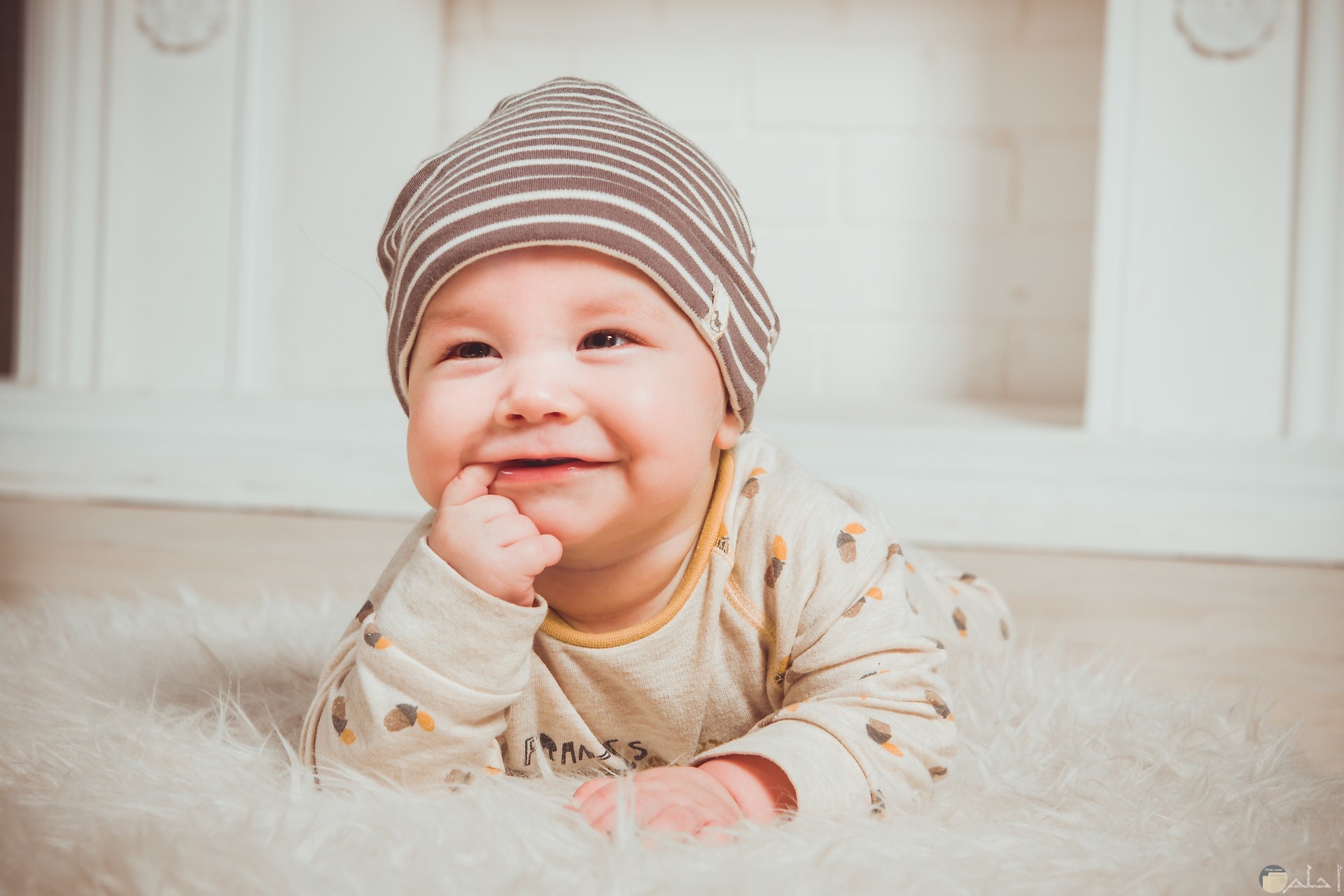 صورة جميلة لطفل صغير بإبتسامة رائعة وهو علي الأرض