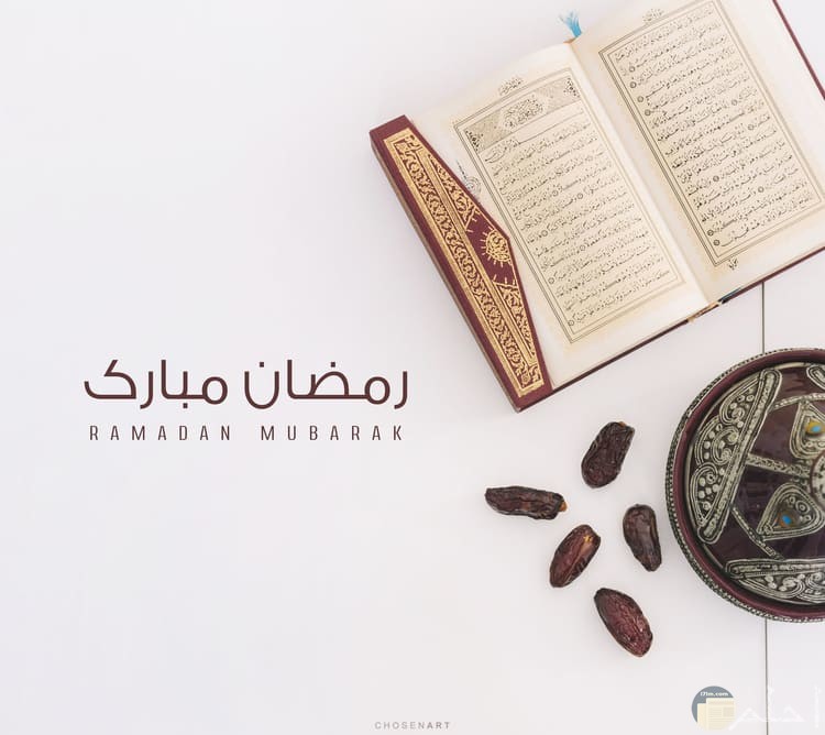 صورة حلوة للتهنئة بشهر رمضان بجملة رمضان مبارك بجانبها مصحف وخمس تمرات