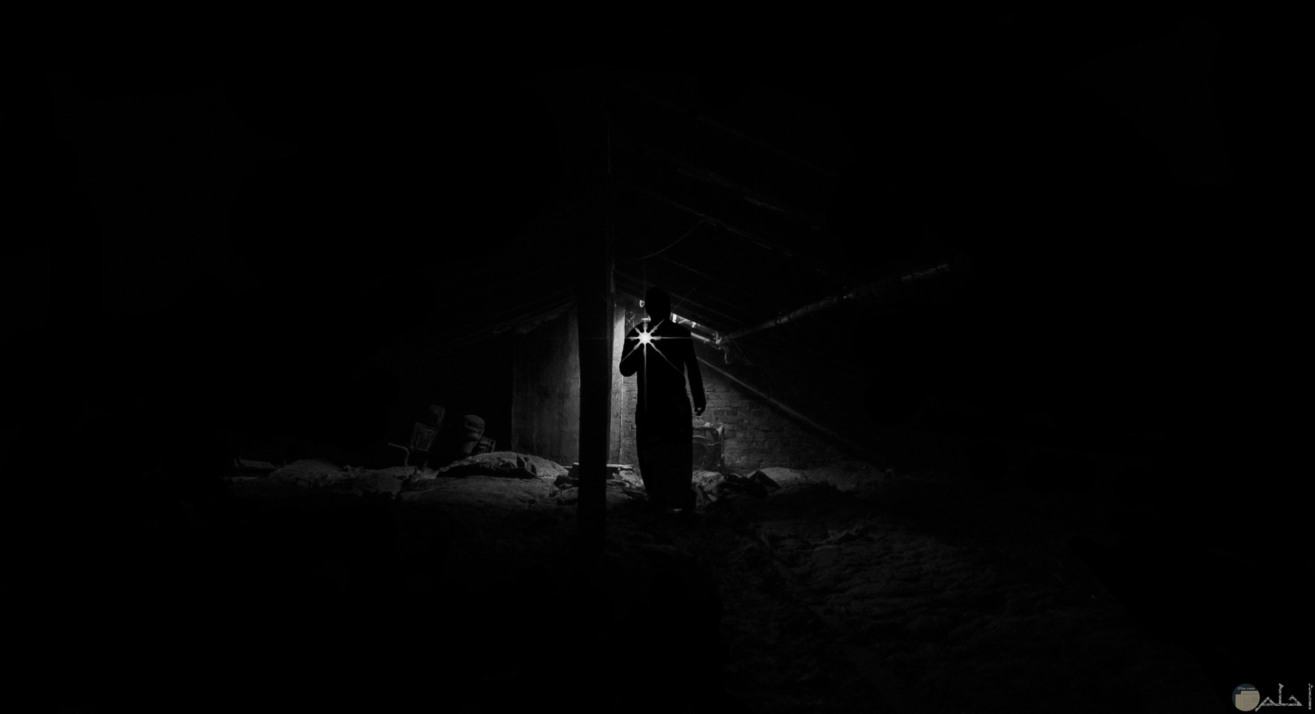 صورة رعب لشخص في مكان مخيف ومظلم ممسك بكشاف للإضاءة فقط