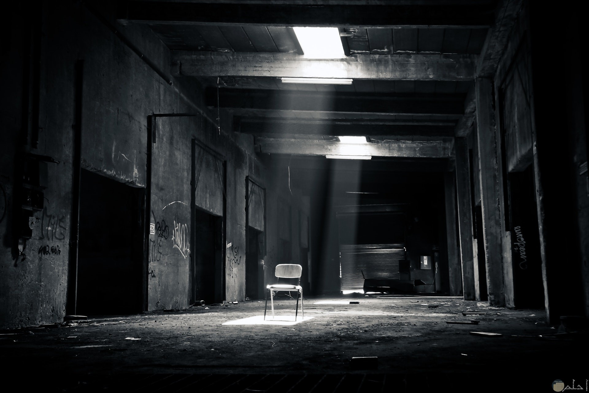 صورة مخيفة بالأبيض والاسود لمكان مهجور ويوجد كرسي يصل له النور