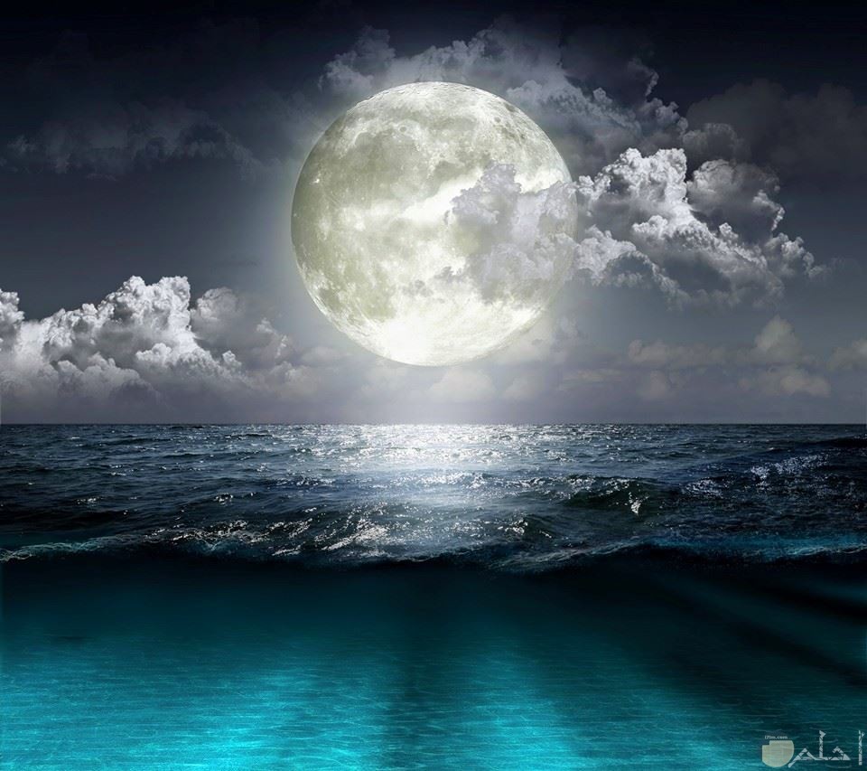 صورة جميلة لقمر كبير أبيض اللون فوق بحر أزرق غامق و غيوم.