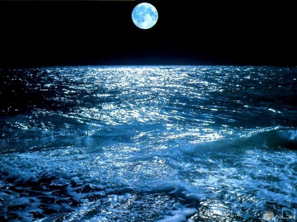 صورة لقمر صغير فوق بحر مع إنعكاس نور القمر عليه.