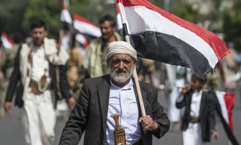 رجل عجوز يحمل العلم اليمني بفخر