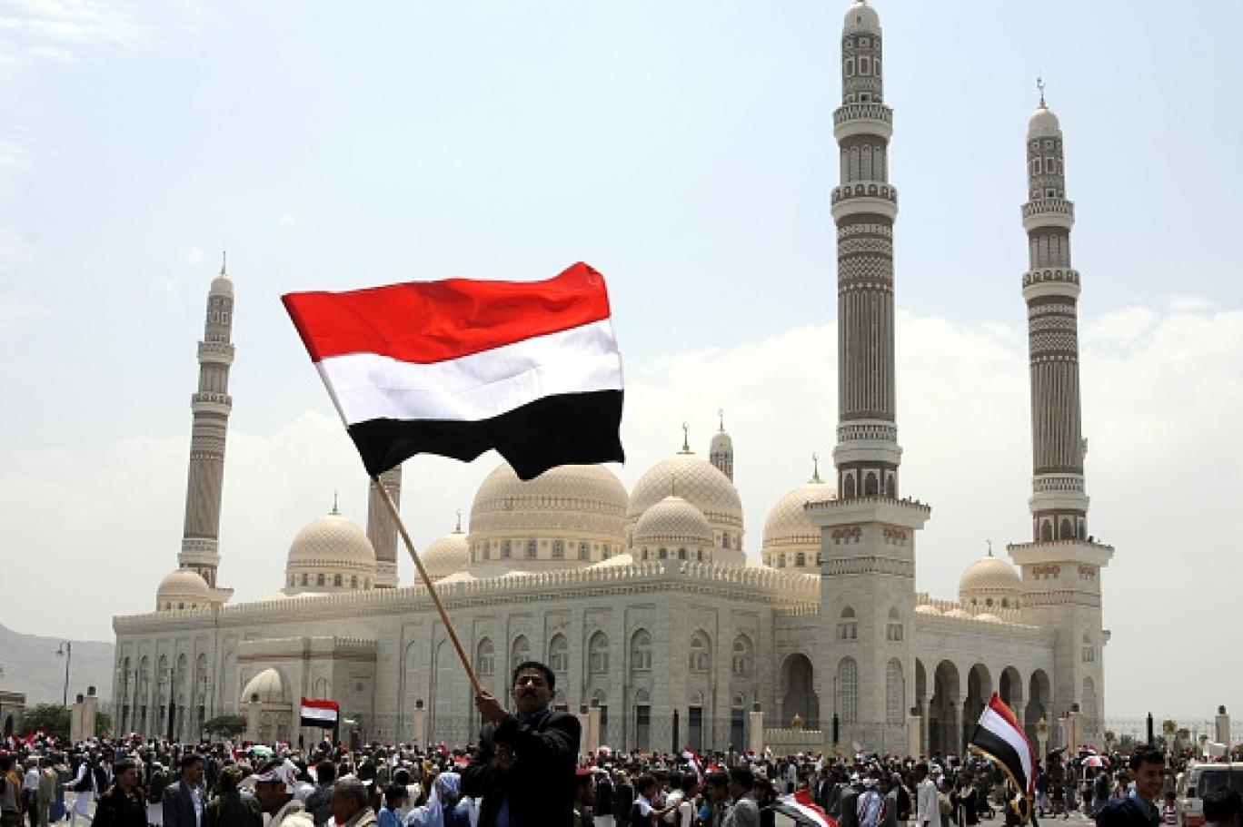 رجل وسط الحشود يحمل العلم اليمني