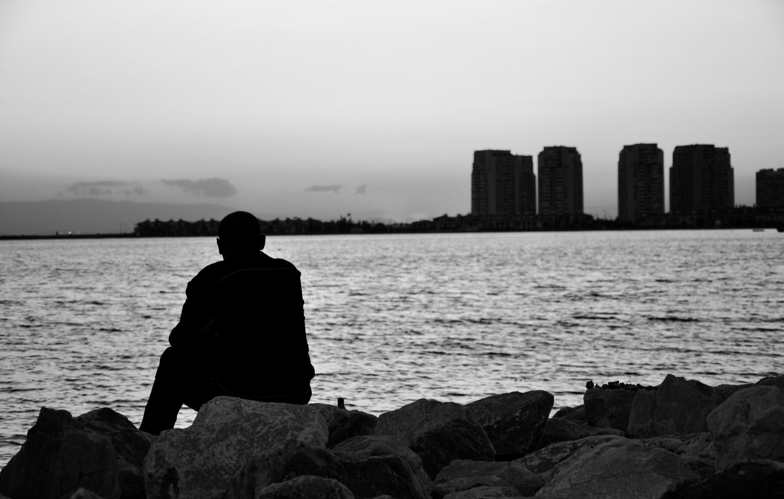 خلفية سوداء رجل يجلس وحيداً علي البحر