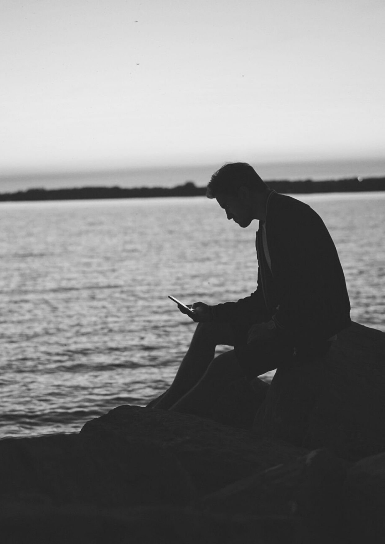 صورة رجل حزين يحمل هاتفه علي البحر